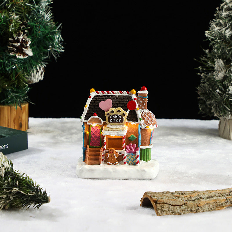 Decorative gingerbread house with candy shop sign on a snowy surface with Christmas trees.
