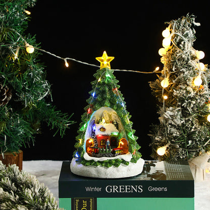 Decorative Christmas tree with lights and a small house on a black box labeled 'Winter Greens'.