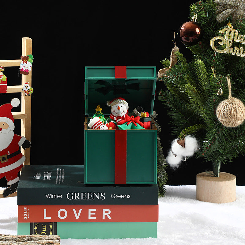 Decorative Christmas scene with a snowman in a box, Santa Claus figure, and Christmas tree.