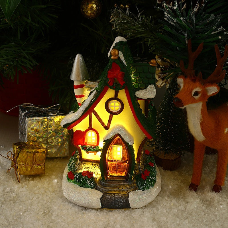 Decorative Christmas scene with a lit gingerbread house, reindeer, and presents.