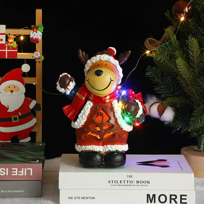 Decorative bear figurine in a Santa outfit with lights, surrounded by Christmas decorations.