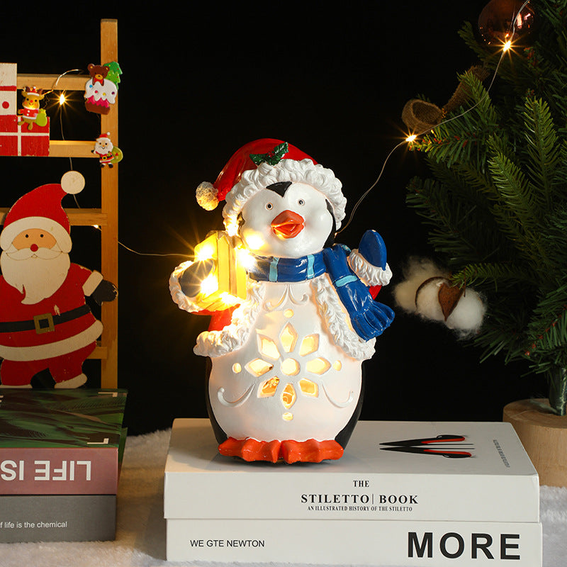 Decorative penguin lamp with string lights on books, surrounded by Christmas decorations.