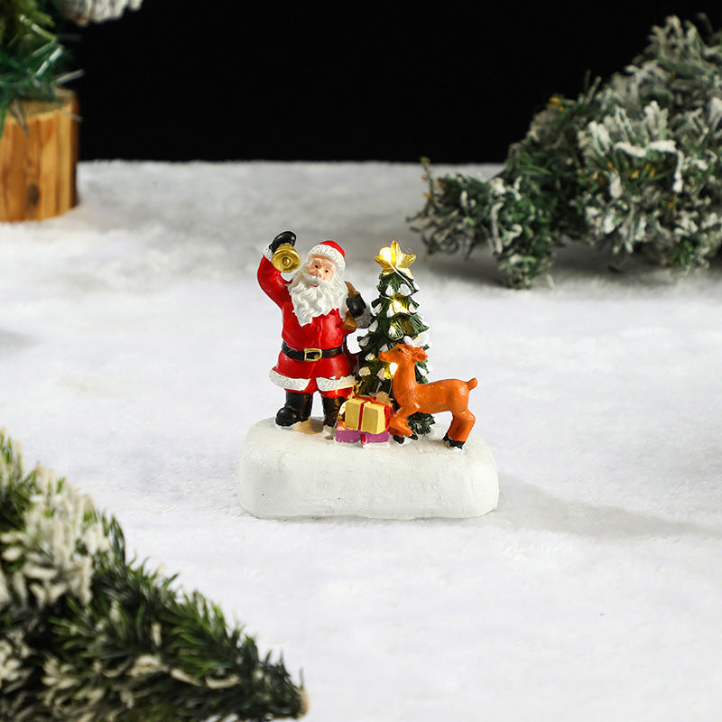 Miniature Santa and deer figure x a Christmas tree in a snowy scene.