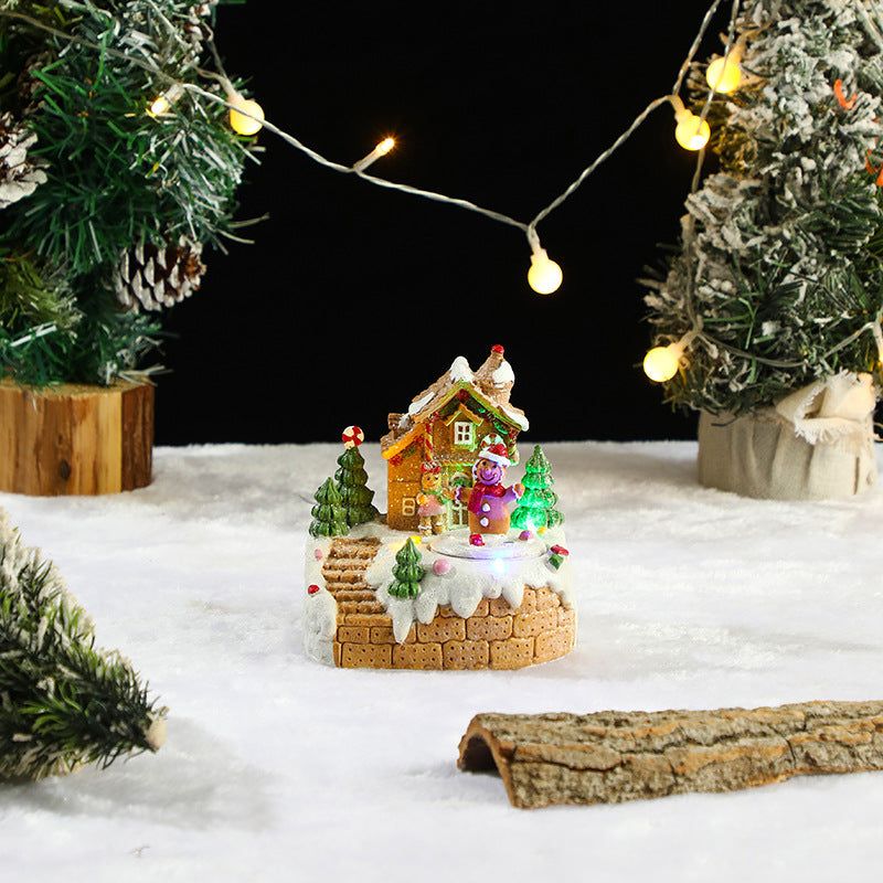 Miniature Christmas scene with a house, trees, and lights on a snowy background