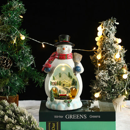 Decorative snowman with a lit scene inside, surrounded by Christmas trees and lights.