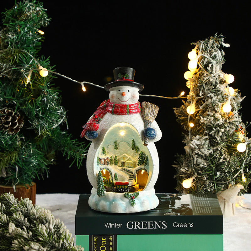 Decorative snowman with a lit scene inside, surrounded by Christmas trees and lights.